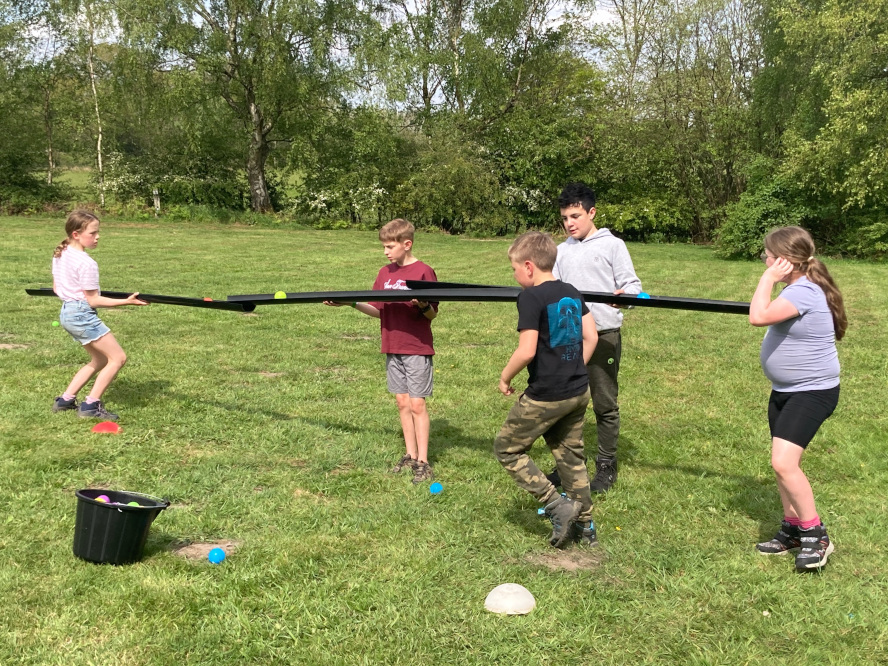 Image of some Cubs and Scouts playing a team-building game involving moving balls along guttering